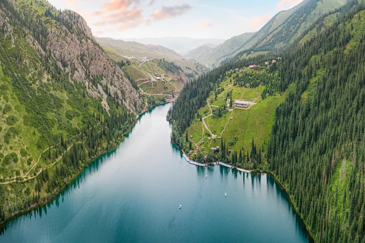 Aerial view of beautiful Kolsai Lakes reflecting colorful sky, mountains and green forest at sunset in Kazakhstan