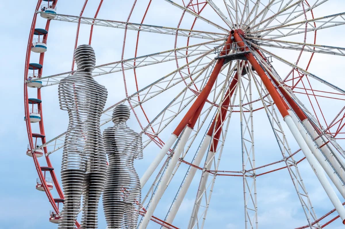 Ali and Nino iconic moving sculpture near the waterfront, symbolizing eternal love, often seen alongside Batumi’s illuminated Ferris wheel and seaside skyline.