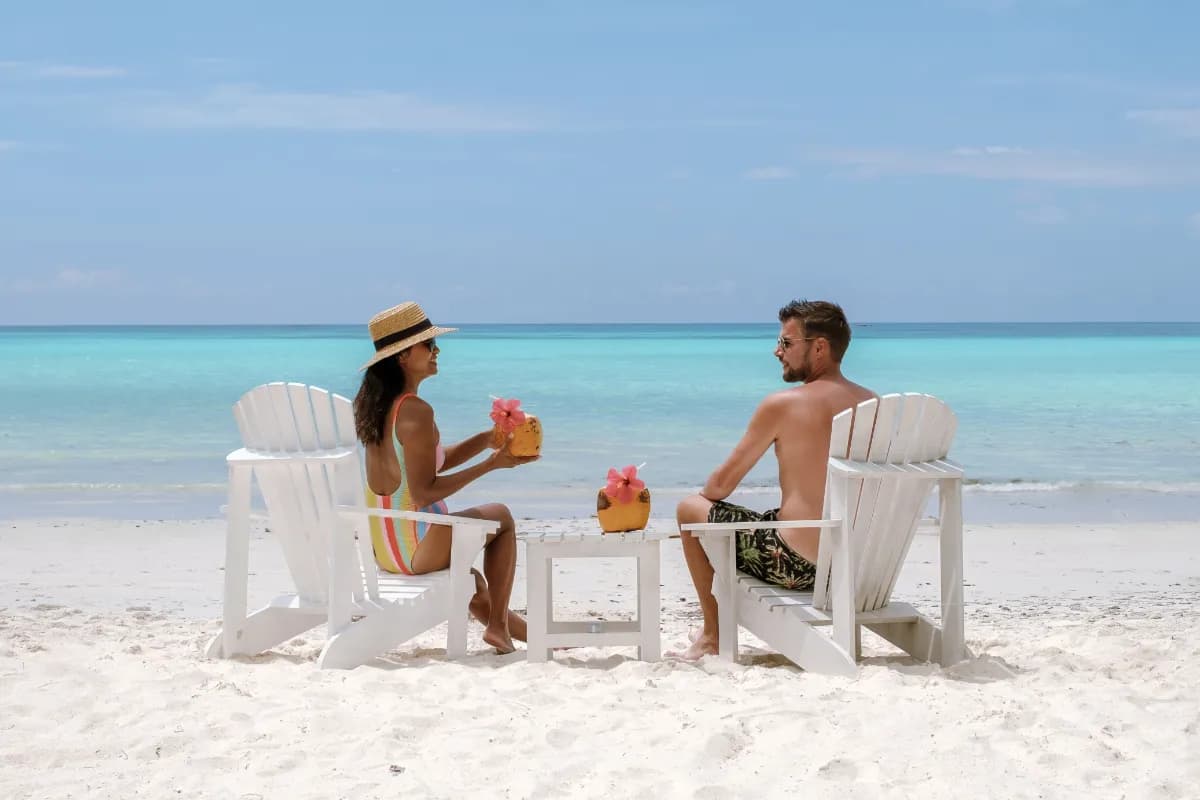 A joyful couple sits under the warm sun at Grand Anse Beach, Praslin Seychelles.
